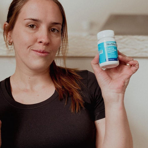 A woman holding Herbion Gastro-intestinal Support Capsules